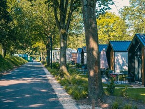 Eine Reihe von Ferienhäusern, verbunden durch einen gepflasterten Weg, der durch ein bewaldetes Gebiet führt.