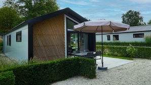 A modern building with a wooden slatted facade, a patio with outdoor seating, and a gravel ground. - Holiday Home in Kaatsheuvel With Terrace (Kaatsheuvel)