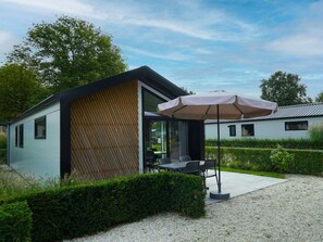 Ein modernes Gebäude mit einer Holzlamellenfassade, einer Terrasse mit Sitzgelegenheiten und einem Kiesgrundstück.