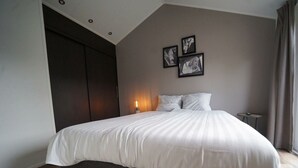 A bedroom with a large bed, dark wooden flooring, a wardrobe, and a wall-mounted light. - Holiday Home in Kaatsheuvel With Terrace (Kaatsheuvel)