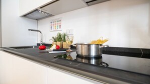 A modern kitchen with a stainless steel pot, a cutting board with vegetables, and a red tomato. - Italianway Comfort - Boncompagni 3B (Milan)
