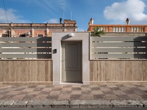 Un bâtiment moderne avec une porte centrale, une clôture en bois et un ciel dégagé.