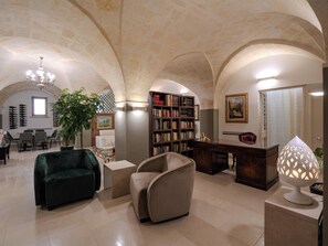 Amplia sala de estar con un techo alto abovedado, una gran estantería, un escritorio y un espacio de descanso acogedor.
