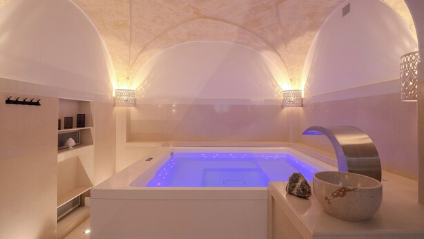 Un spa moderno con piscina climatizada, techos abovedados e iluminación ambiental.