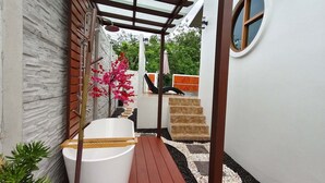 Ein Wellnessbereich mit Badewanne, Holzterrasse und Steinwand.