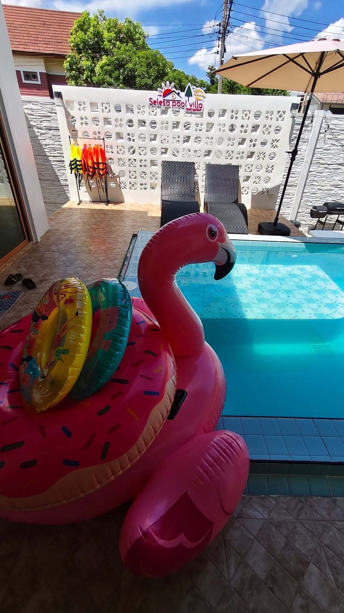 A swimming pool with inflatable flamingo floats and lounge chairs.