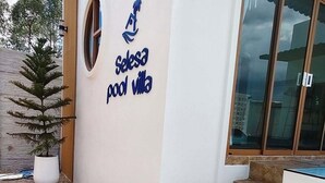 Ein Gebäude mit einem Schild, auf dem 'Selena Pool Villa' steht, einer Treppe und Kübelpflanzen.