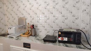 Eine Küche mit gefliestem Rückspritzschutz, einer Mikrowelle, einem Toaster und einem Geschirrgestell.