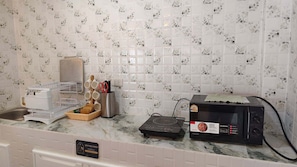 Una cocina con salpicadero de azulejos, microondas, tostadora y escurreplatos.