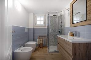 A bathroom with a shower, two sinks, a toilet, and a window. - This cozy apartment, perfect for two people, is located in a shared villa but has its own private access. It features a shared garden and a large furnished patio for exclusive use. The accommodation is located in Marina di Pulsano, a well-served seaside  (Marina di Pulsano)