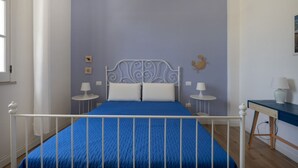 Quarto com cama, duas mesas de cabeceira, escrivaninha e cadeira.