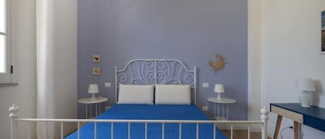 A bedroom with a bed, two bedside tables, a desk, and a chair.