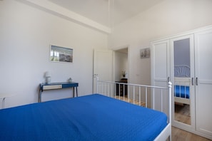 Un dormitorio con cama, escritorio, armario y puerta que da a otra habitación.
