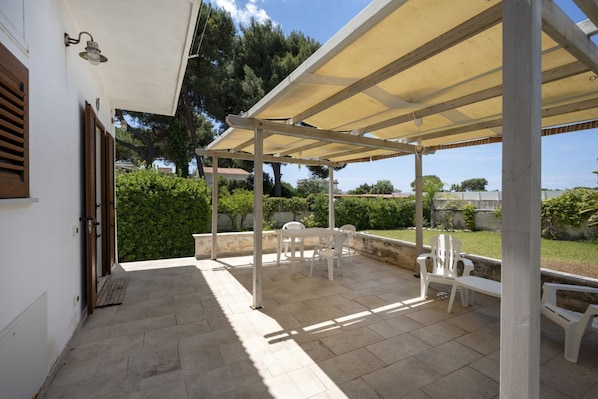 Un patio al aire libre con pérgola, asientos y vistas al entorno verde.