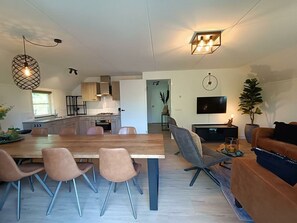 A modern interior with a dining area, kitchen, living room, and a TV. - Secret van Otterlo Luxe 10 (Otterlo)