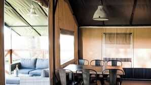 Ett takförsett utomhusområde med ett bord och stolar, en soffa och en hängande lampa.