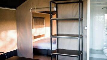 A room with a bunk bed, a metal shelf unit, and a shower area.