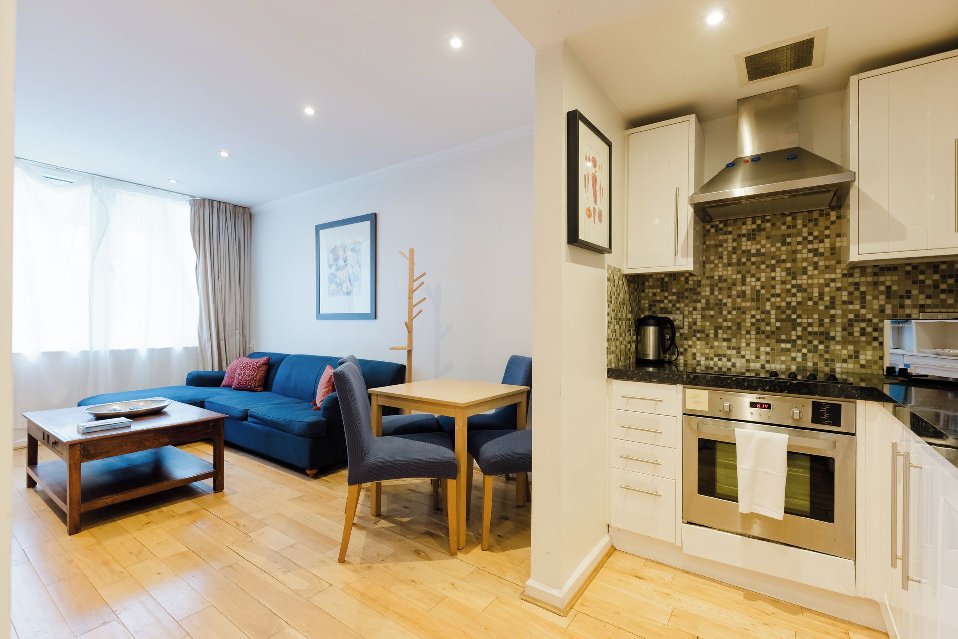 A modern apartment with a living room, dining area, and kitchen.