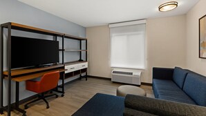 Una sala moderna con televisión, sofá y un escritorio con silla.