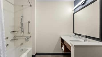 A modern bathroom with a bathtub, a shower with grab bars, a vanity with a mirror, and a towel rack.