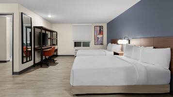 A hotel room with a large bed, a desk with a computer, and a TV.