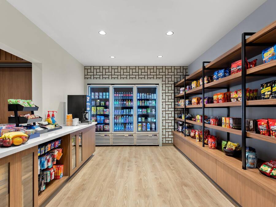 Un kiosque proposant des collations et des boissons, avec des boissons réfrigérées et une variété de produits alimentaires présentés sur des étagères.
