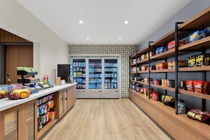 A snack and beverage kiosk with refrigerated drinks and a variety of snacks on shelves.