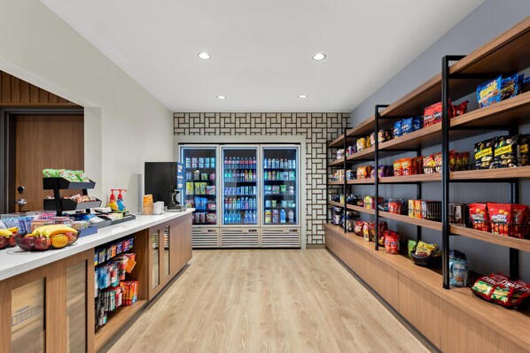A snack and beverage kiosk with refrigerated drinks and a variety of snacks on shelves.