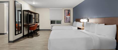 Una habitación de hotel con una cama grande, un escritorio con computadora y televisor.