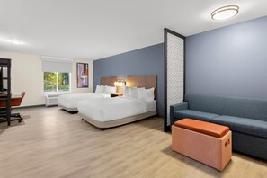 A hotel room with two beds, a sofa, a desk, and a window.