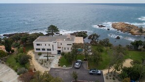 A modern two-story house with a flat roof, surrounded by a landscaped garden and a view of the ocean. - Stunning waterfront villa with a private beach in CANELLA (Sari-Solenzara)