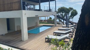 A modern two-story building with a pool, outdoor seating, and a view of the sea. - Stunning waterfront villa with a private beach in CANELLA (Sari-Solenzara)