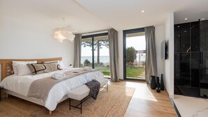 A bedroom with a large bed, a view of the sea, and a modern bathroom. - Stunning waterfront villa with a private beach in CANELLA (Sari-Solenzara)