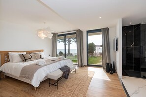 A bedroom with a large bed, a view of the sea, and a modern bathroom. - Stunning waterfront villa with a private beach in CANELLA (Sari-Solenzara)