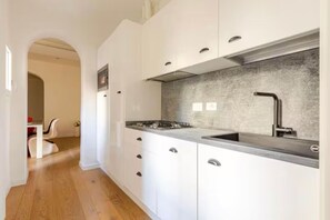 Una cucina moderna con mobili bianchi, un piano di lavoro in granito e un lavello in acciaio inossidabile.