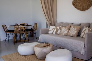 Ein modernes Wohnzimmer mit einer Couch, Hocker, einem Esstisch mit Stühlen und einer Wanddekoration.