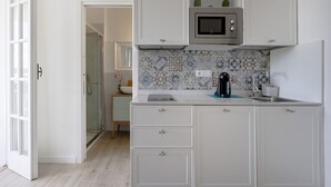 A kitchen with white cabinets, a microwave, and a tiled backsplash. - Large studio apartment perfect for two people, is located in a shared villa but has its own private access. It features a shared garden and a large furnished patio for exclusive use. The accommodation is located in Marina di Pulsano, a well-served seasid (Marina di Pulsano)