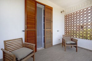 A balcony with two wooden chairs, a wooden door with louvered panels, and a decorative lattice wall. - Large studio apartment perfect for two people, is located in a shared villa but has its own private access. It features a shared garden and a large furnished patio for exclusive use. The accommodation is located in Marina di Pulsano, a well-served seasid (Marina di Pulsano)