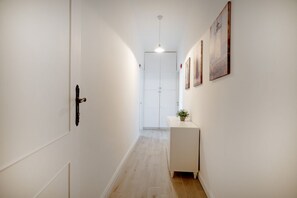 Ein Flur mit einer weißen Tür, einem kleinen weißen Schrank und einer Pendelleuchte.