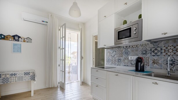 A kitchen with white cabinets, a microwave, a sink, and a patterned backsplash. - Large studio apartment perfect for two people, is located in a shared villa but has its own private access. It features a shared garden and a large furnished patio for exclusive use. The accommodation is located in Marina di Pulsano, a well-served seasid (Marina di Pulsano)