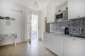 A kitchen with white cabinets, a microwave, a sink, and a patterned backsplash. - Large studio apartment perfect for two people, is located in a shared villa but has its own private access. It features a shared garden and a large furnished patio for exclusive use. The accommodation is located in Marina di Pulsano, a well-served seasid (Marina di Pulsano)