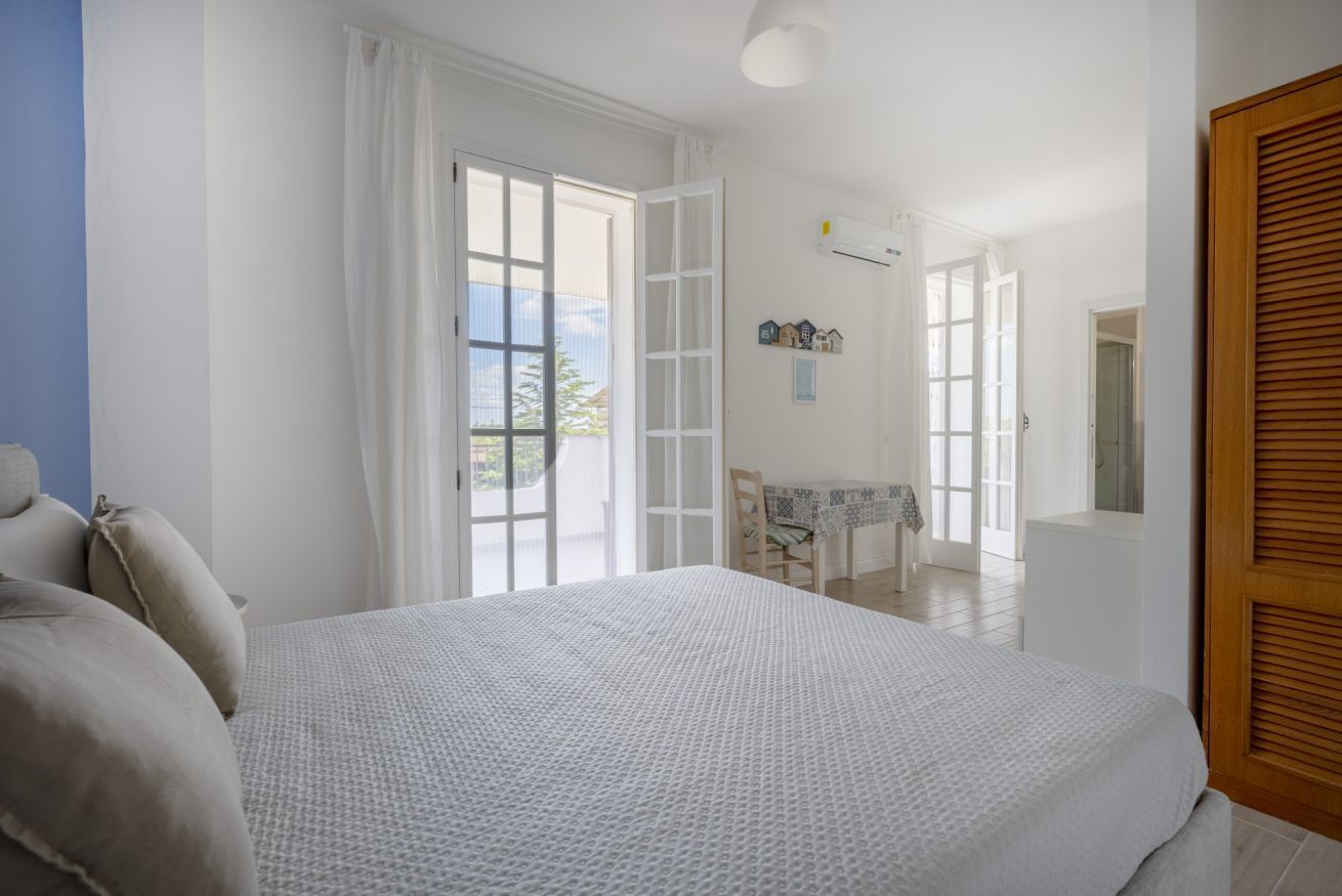 Un dormitori amb un llit gran, una taula i una cadira a l'habitació adjacent.
