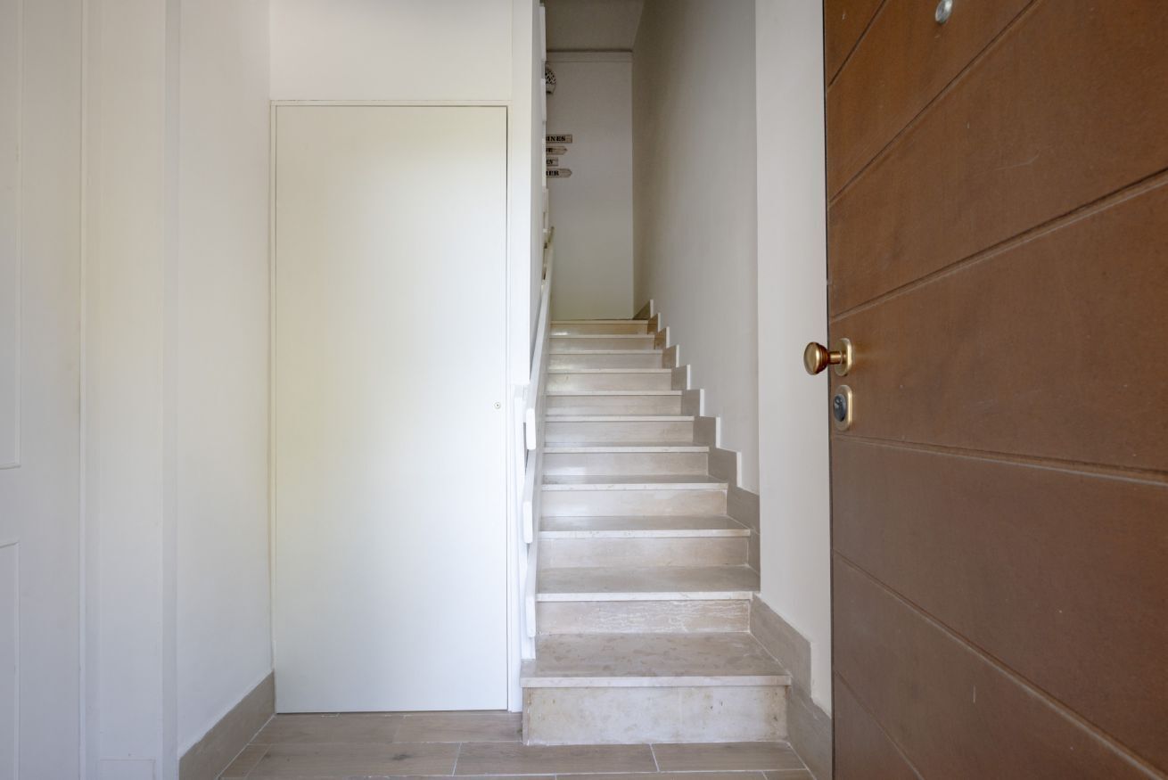 Un escalier menant à une porte dotée d’une poignée en laiton.