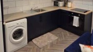 Een praktische keuken met een wasmachine, een magnetron en een kookplaat.