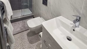 Een moderne badkamer met een douchecabine van glas, een witte wastafel en een grote spiegel.
