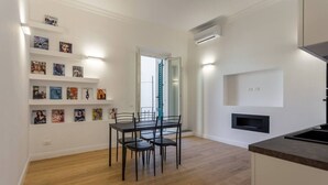 Una cucina moderna con piano cottura integrato, una zona pranzo con tavolo e sedie e un televisore montato a parete.