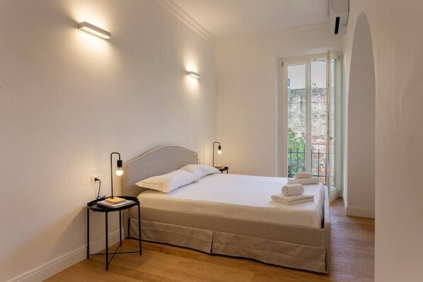 Ein Schlafzimmer mit Bett, Nachttischlampen, einem Nachttisch und einem Fenster mit Blick.