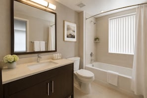 A bathroom with a vanity, toilet, bathtub, and a shower area. - Merona Grand Hotel (Toronto)