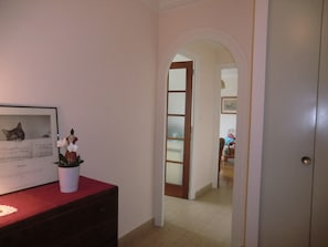 A hallway with a door leading to another room, a framed picture on a dresser, and a potted plant. - 51m² apartment, 1 bedroom, in the very heart of the city with a garage (Aix-les-Bains)