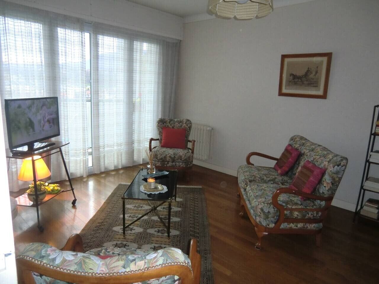 A living room with a sofa, armchair, and a television on a stand.